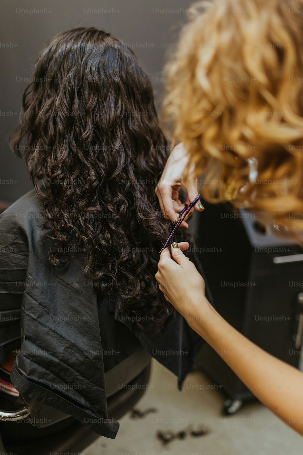 a woman cutting another woman's hair with scissors