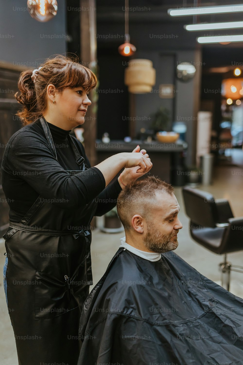 a woman cutting a man's hair in a salon