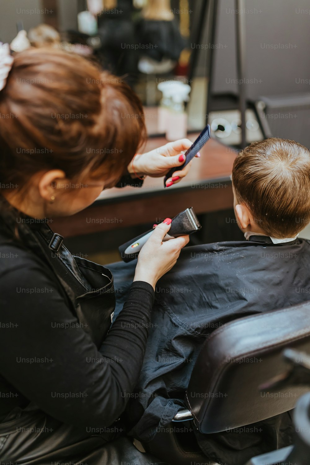 a woman cutting a boy's hair in a salon