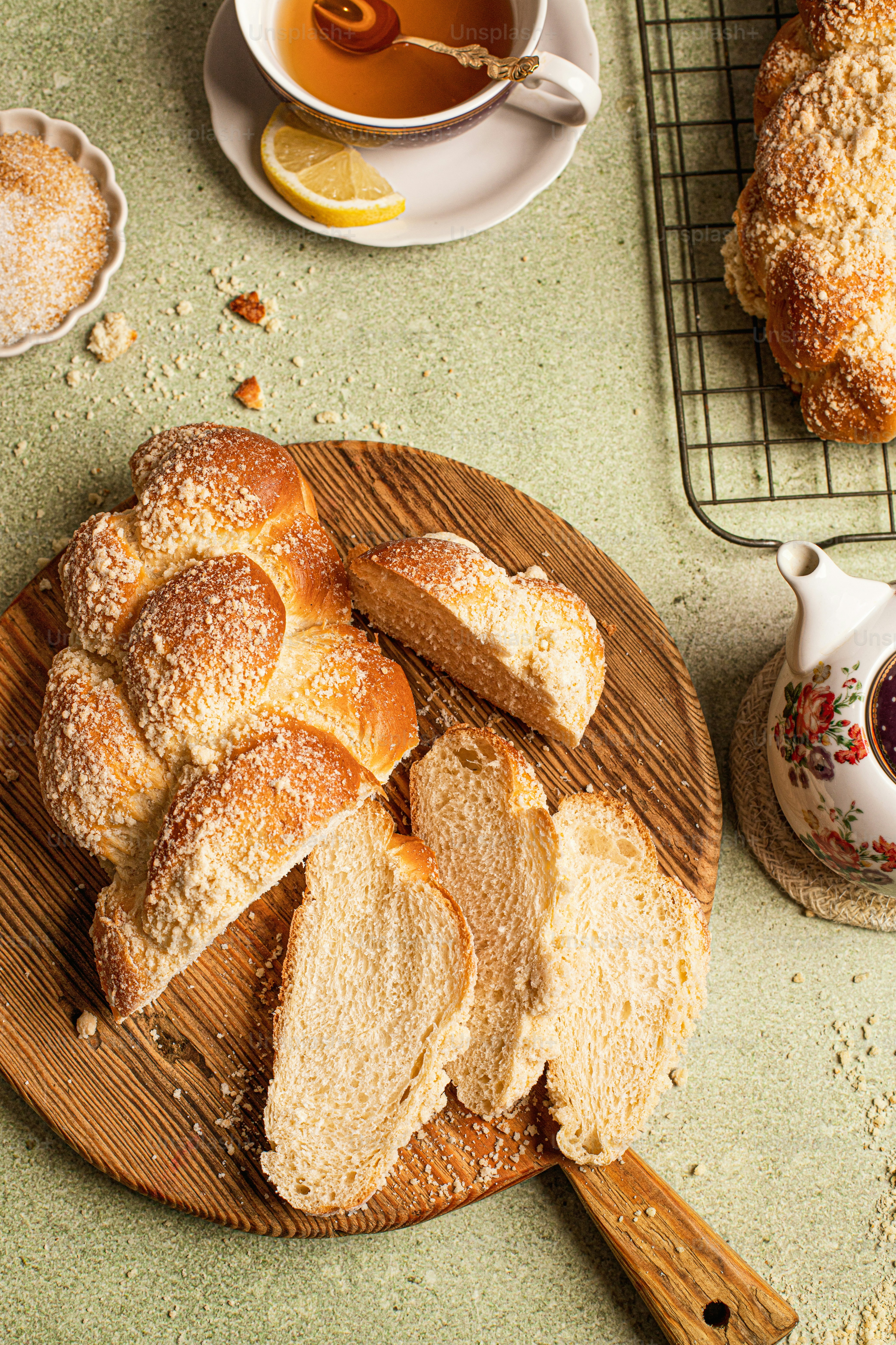 a wooden board topped with loaves of bread next to a cup of tea