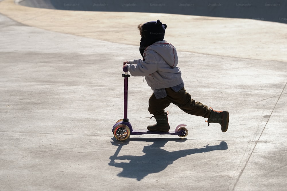 uma criança pequena andando de scooter em uma calçada