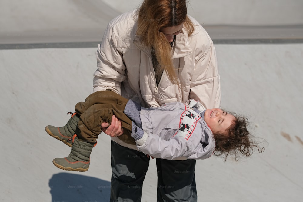 a woman holding a child on a skateboard ramp