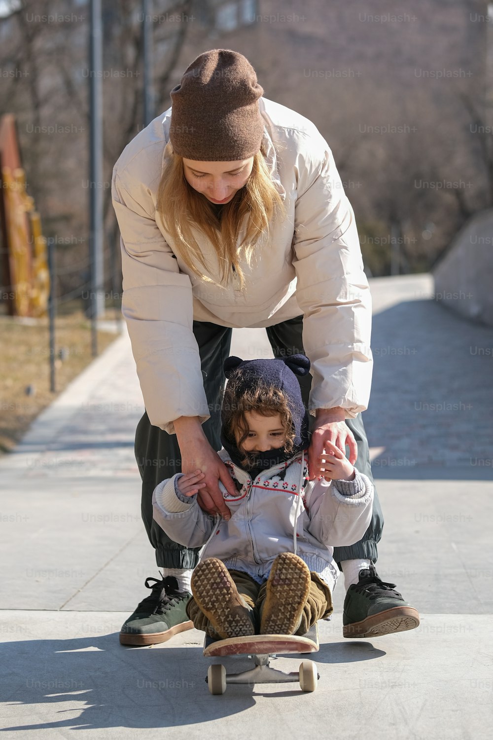 a woman helping a child ride a skateboard