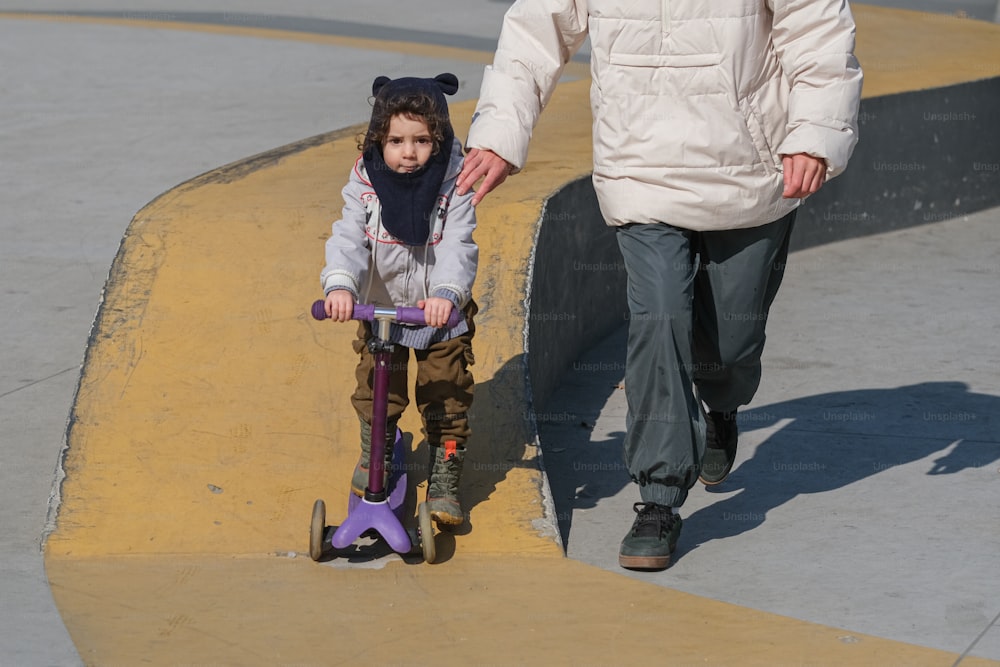 a little girl riding a scooter next to a man