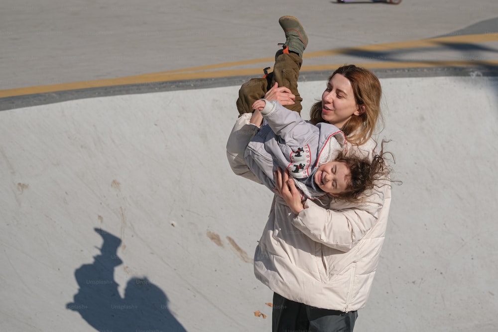 a woman holding a child on a skateboard ramp
