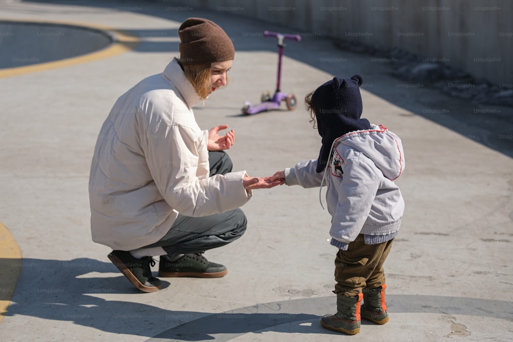 a man kneeling down next to a small child