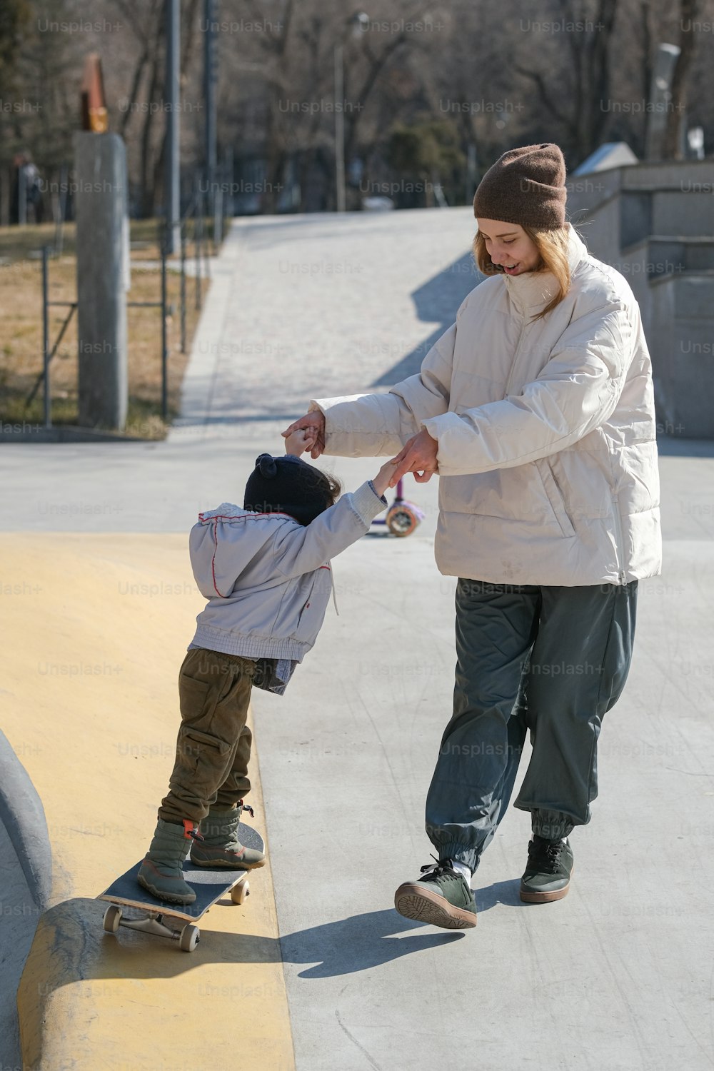 Una mujer enseñando a un niño a andar en monopatín