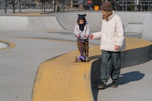 a young girl riding a skateboard next to an adult