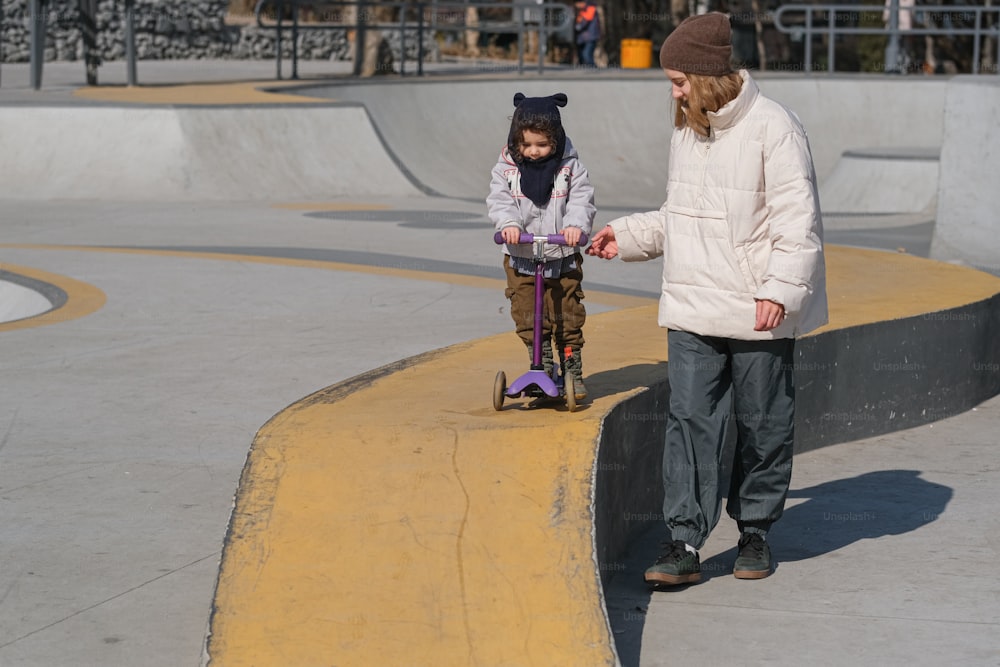 a young girl riding a skateboard next to an adult