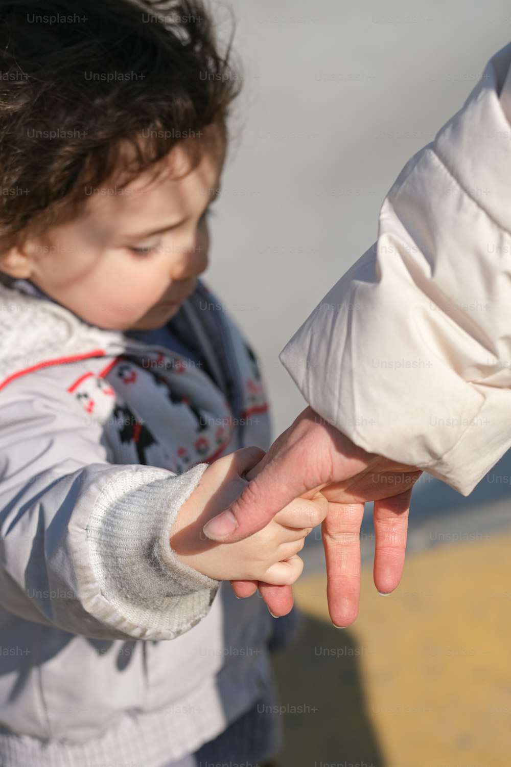 uma criança pequena segurando a mão de um adulto
