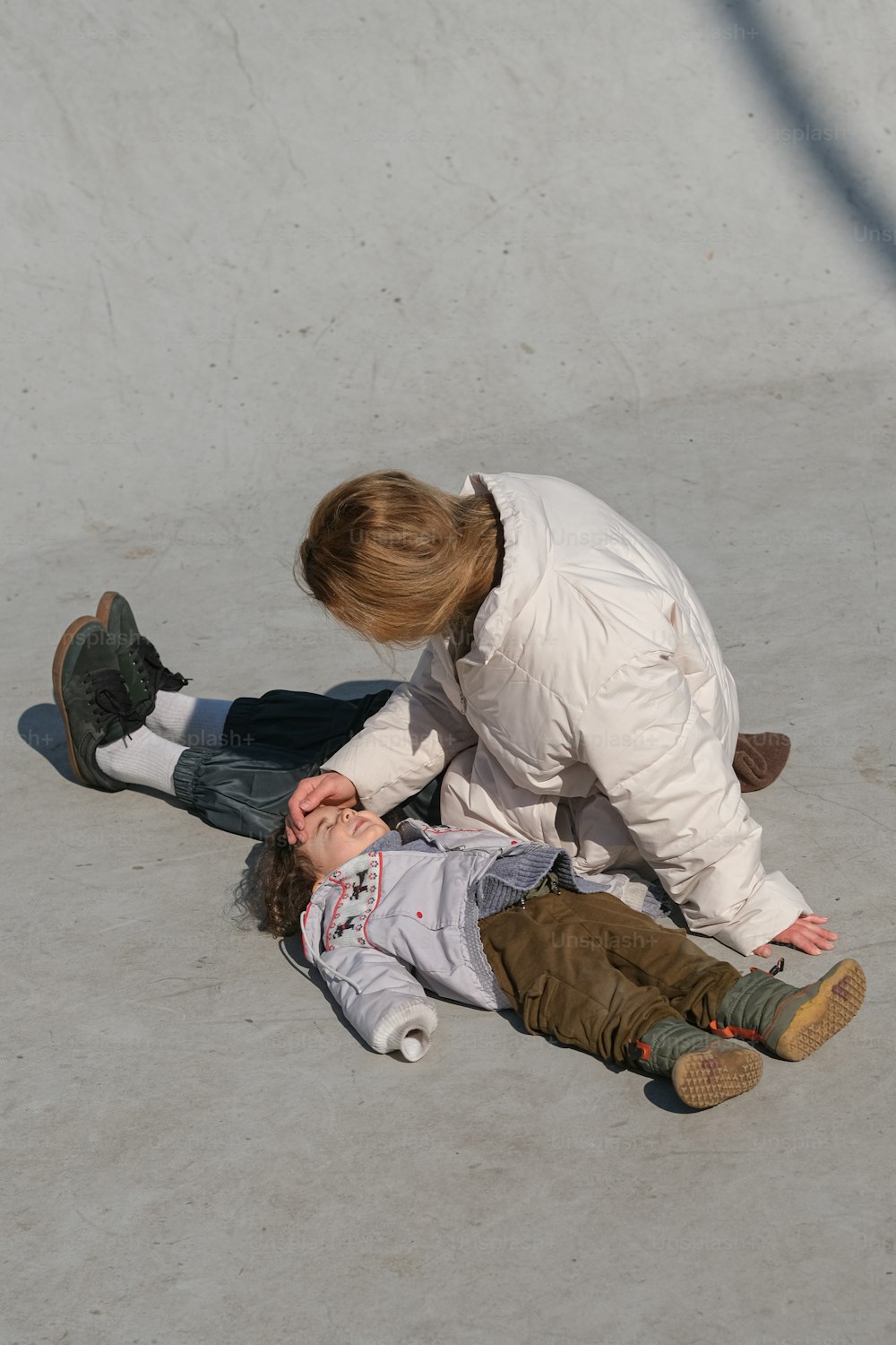 a young boy sitting on the ground next to a young boy