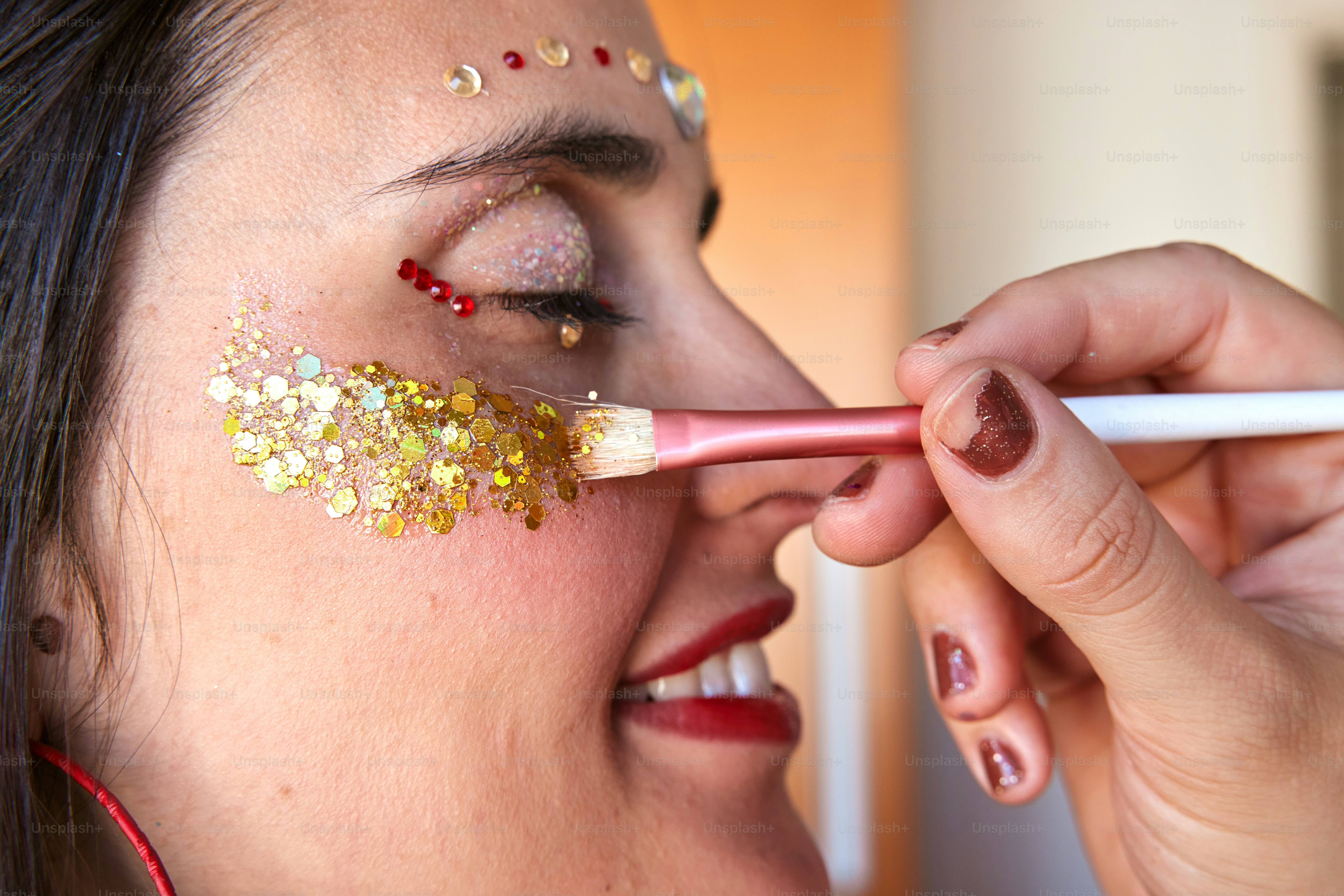 a woman is putting glitter on her face