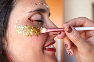 a woman is putting glitter on her face