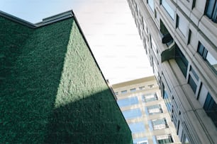 a tall building with a green roof next to a tall building