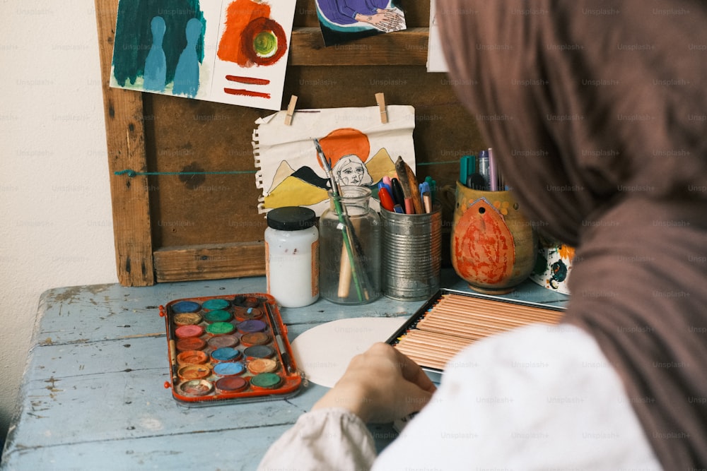 Eine Frau im Hijab malt ein Bild auf einen Tisch