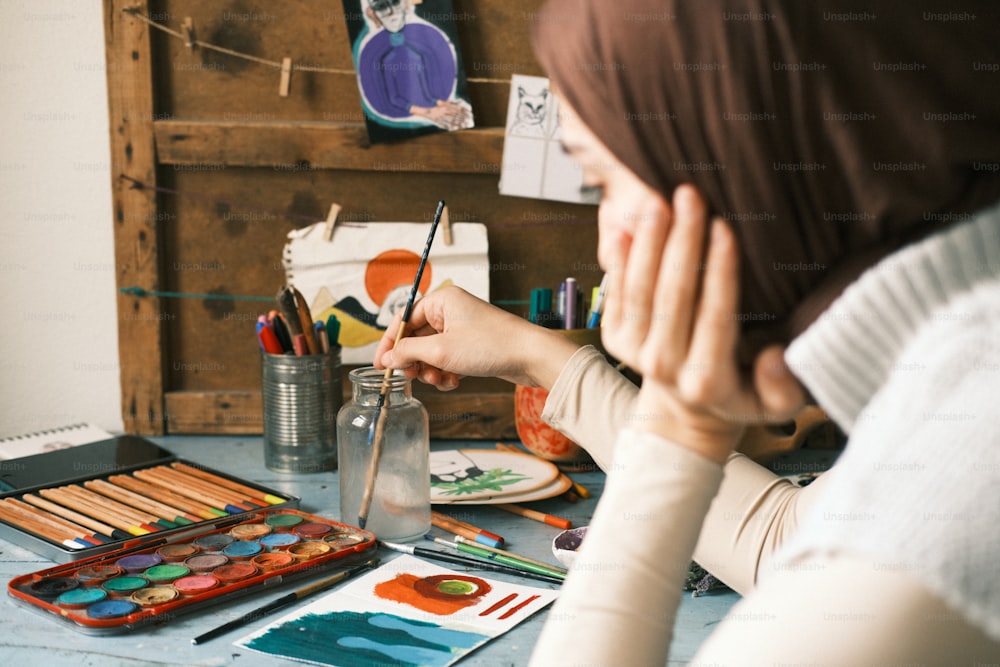 a woman sitting at a table with art supplies