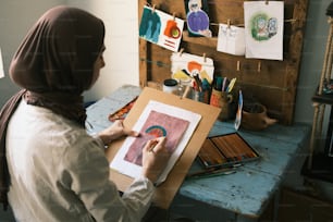 a woman in a hijab is drawing on a piece of paper