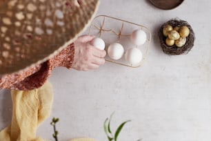 una persona colocando huevos en una canasta sobre una mesa