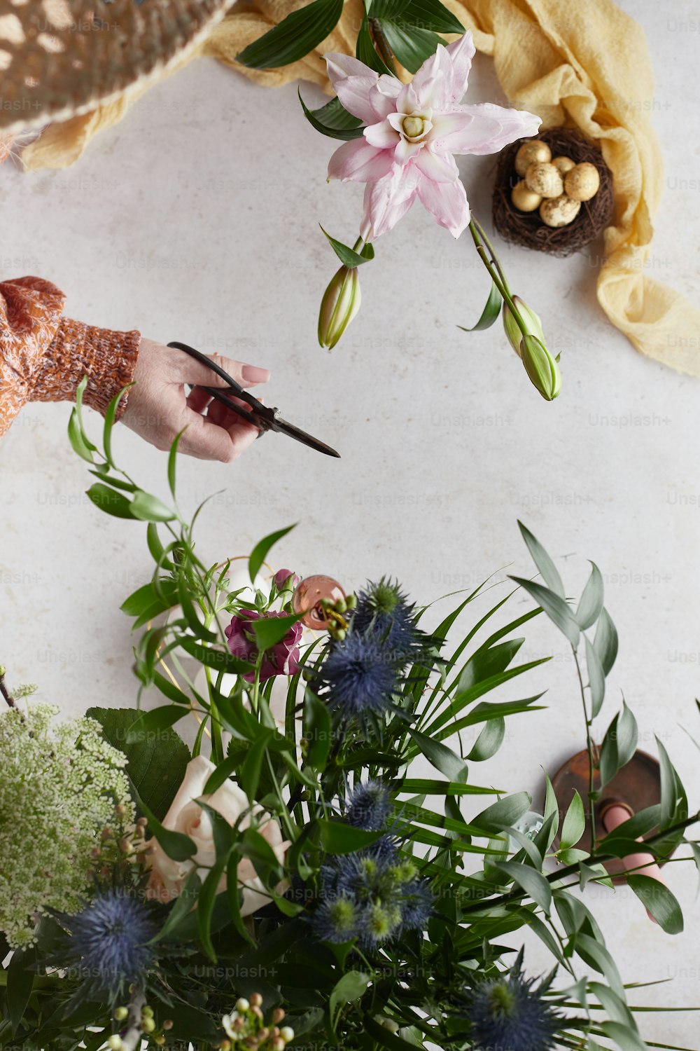 Eine Person, die Blumen mit einer Schere auf einem Tisch schneidet