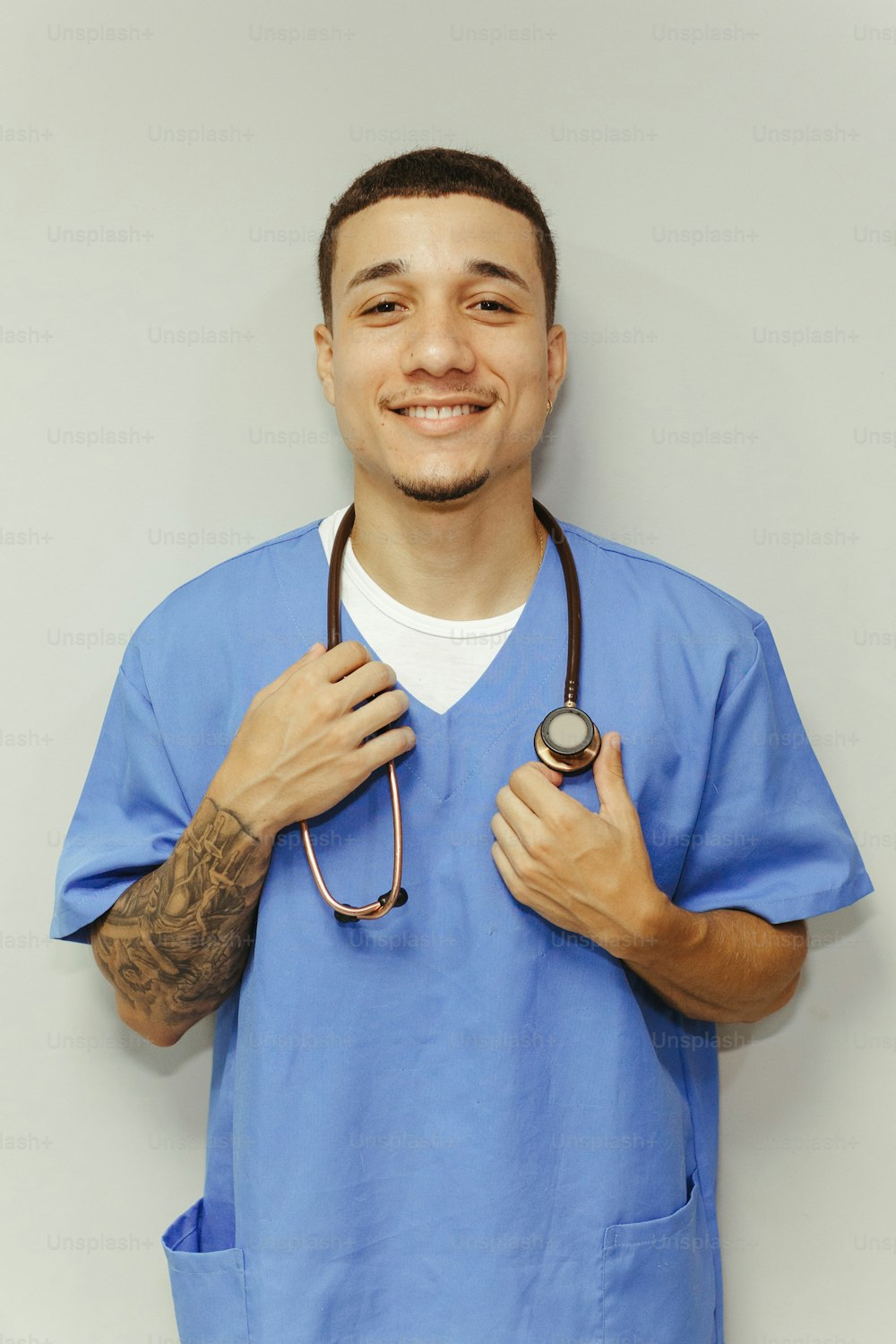 a man in a blue scrub suit holding a stethoscope