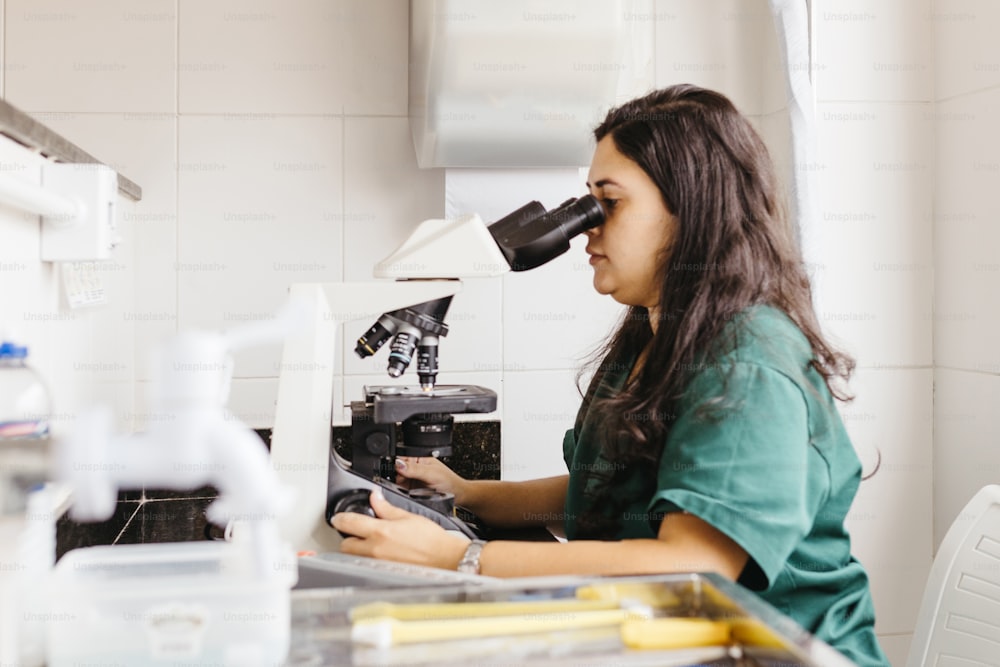 a woman looking through a microscope at something