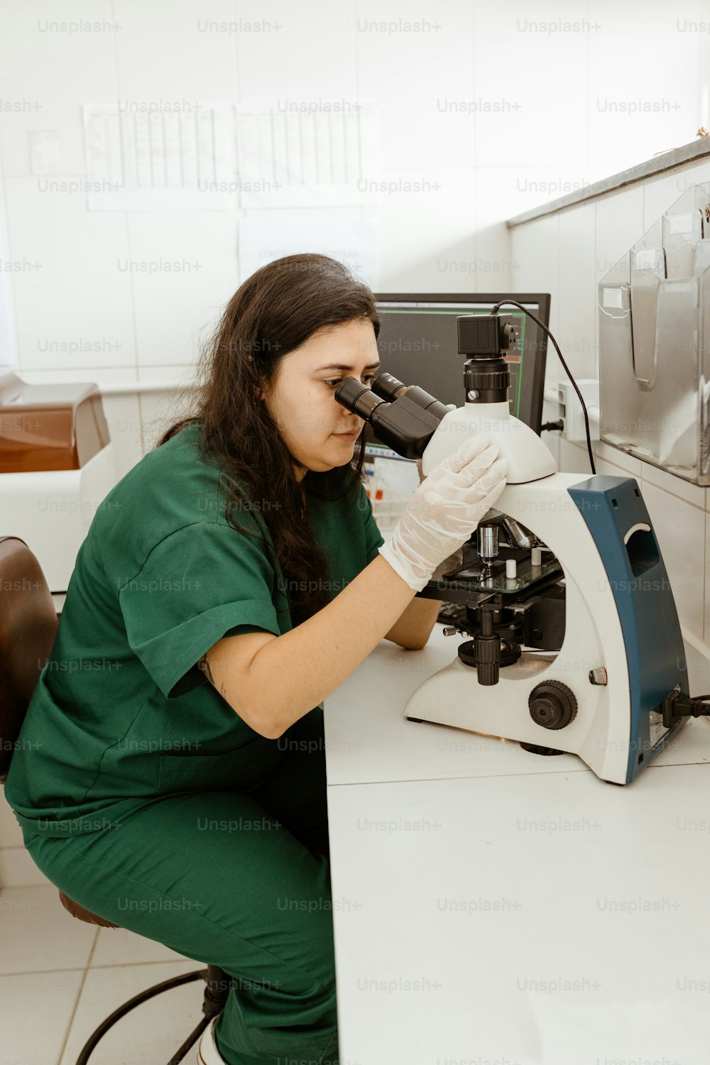 a woman looking through a microscope in a lab