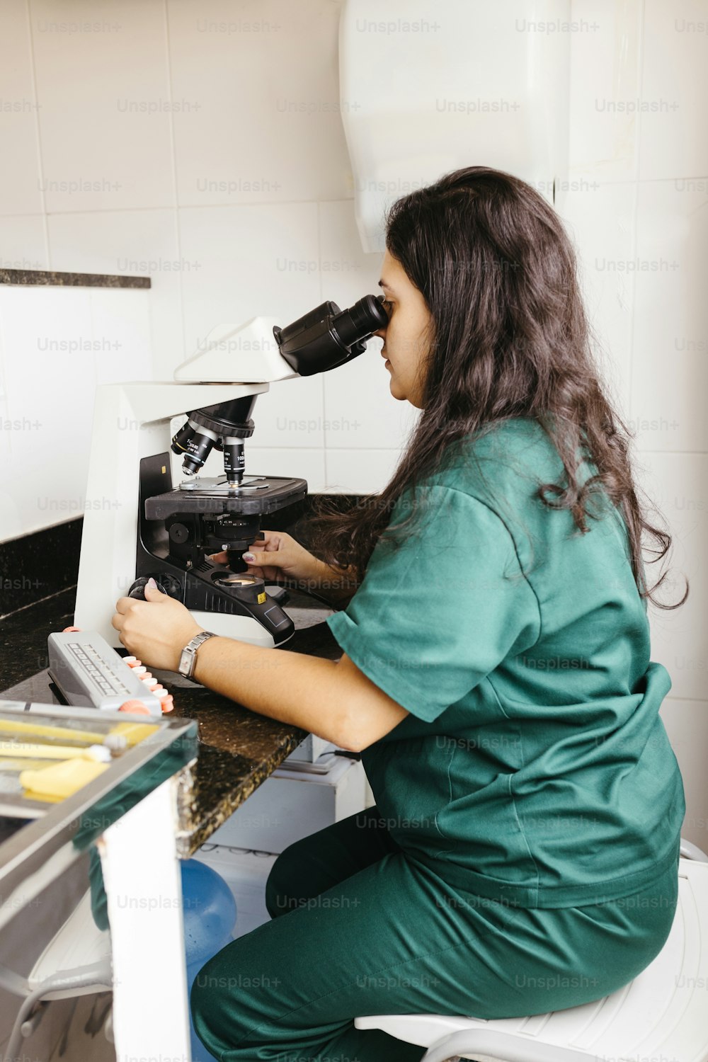 Eine Frau sitzt mit einem Mikroskop in der Hand am Schreibtisch