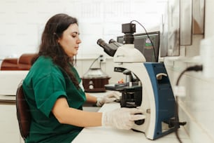 현미경을 통해 보고 있는 녹색 셔츠를 입은 여자