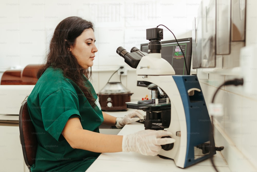 a woman in a green shirt looking through a microscope