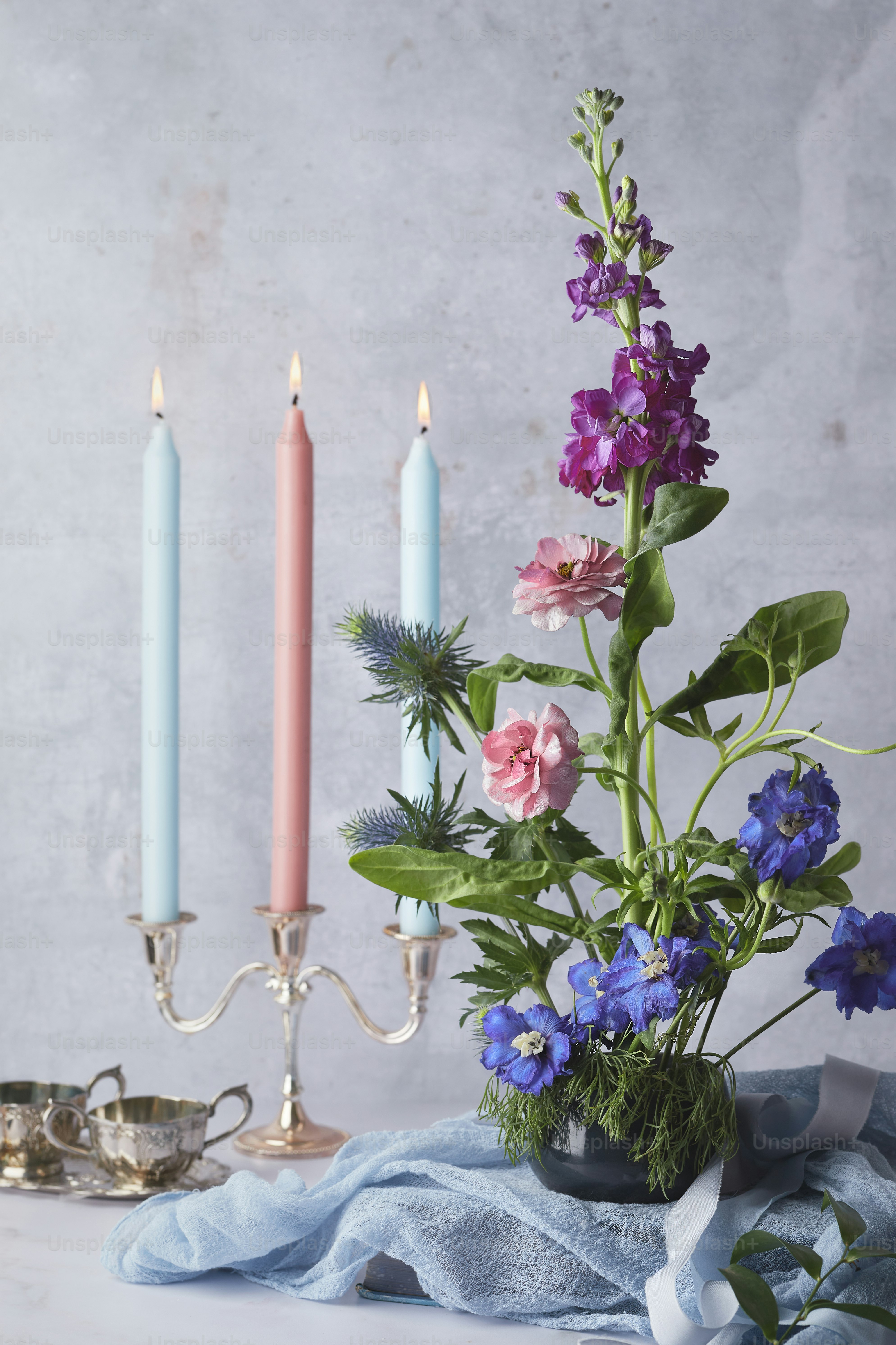 un vase rempli de fleurs à côté de deux bougies