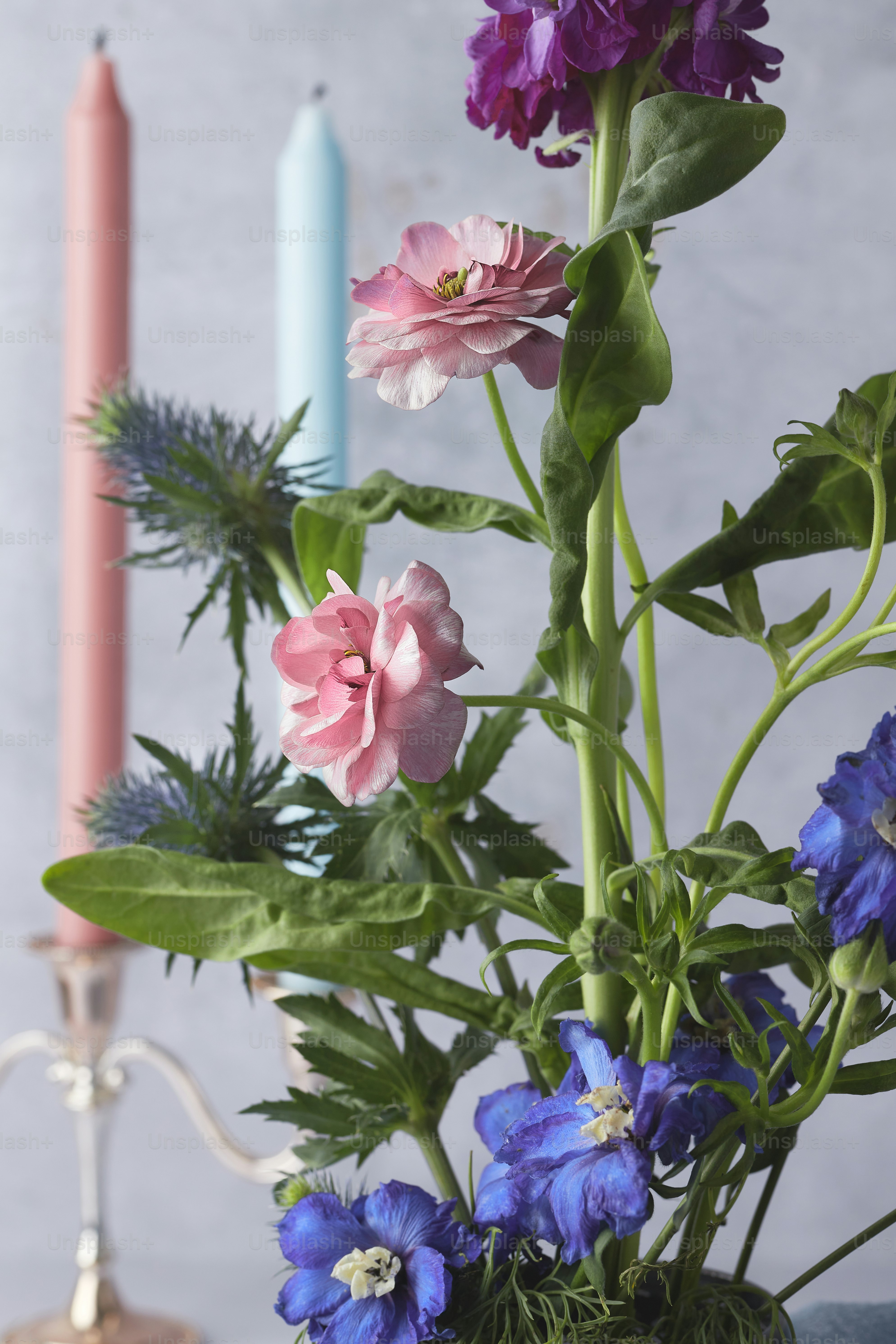 un vase rempli de fleurs à côté d’une bougie