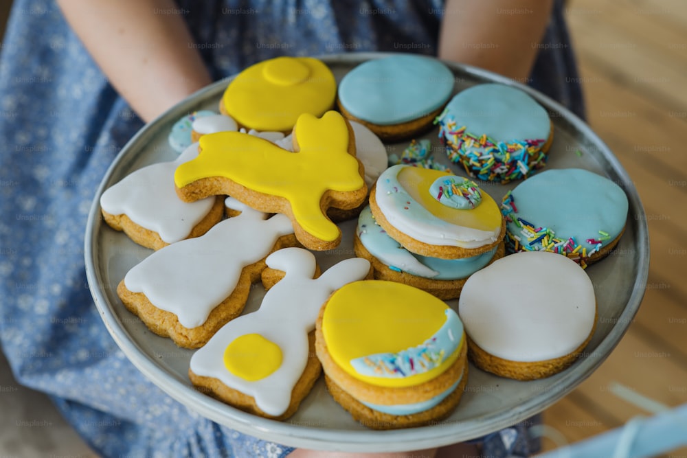 a person holding a plate of decorated cookies