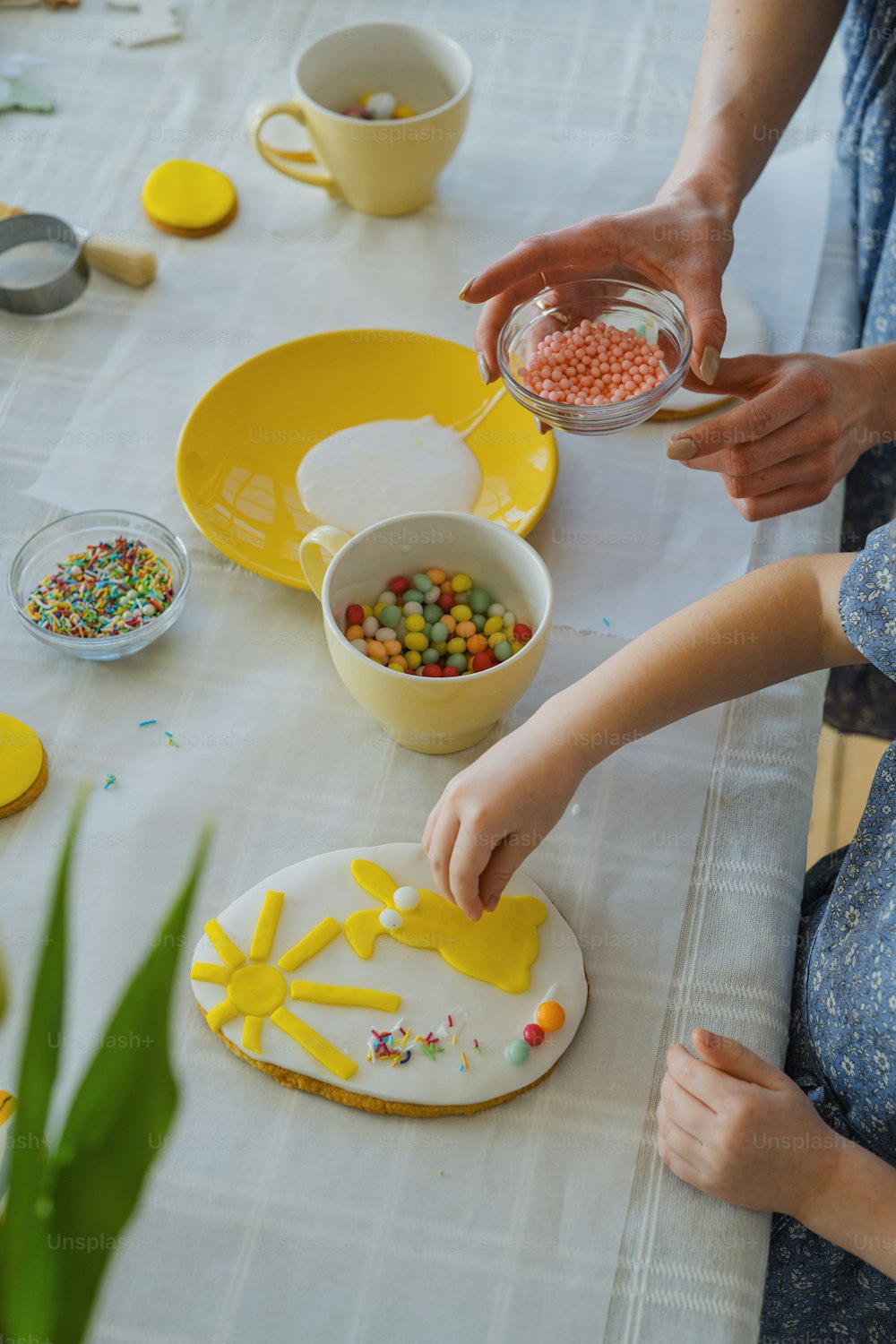 a woman is decorating a cake with yellow icing
