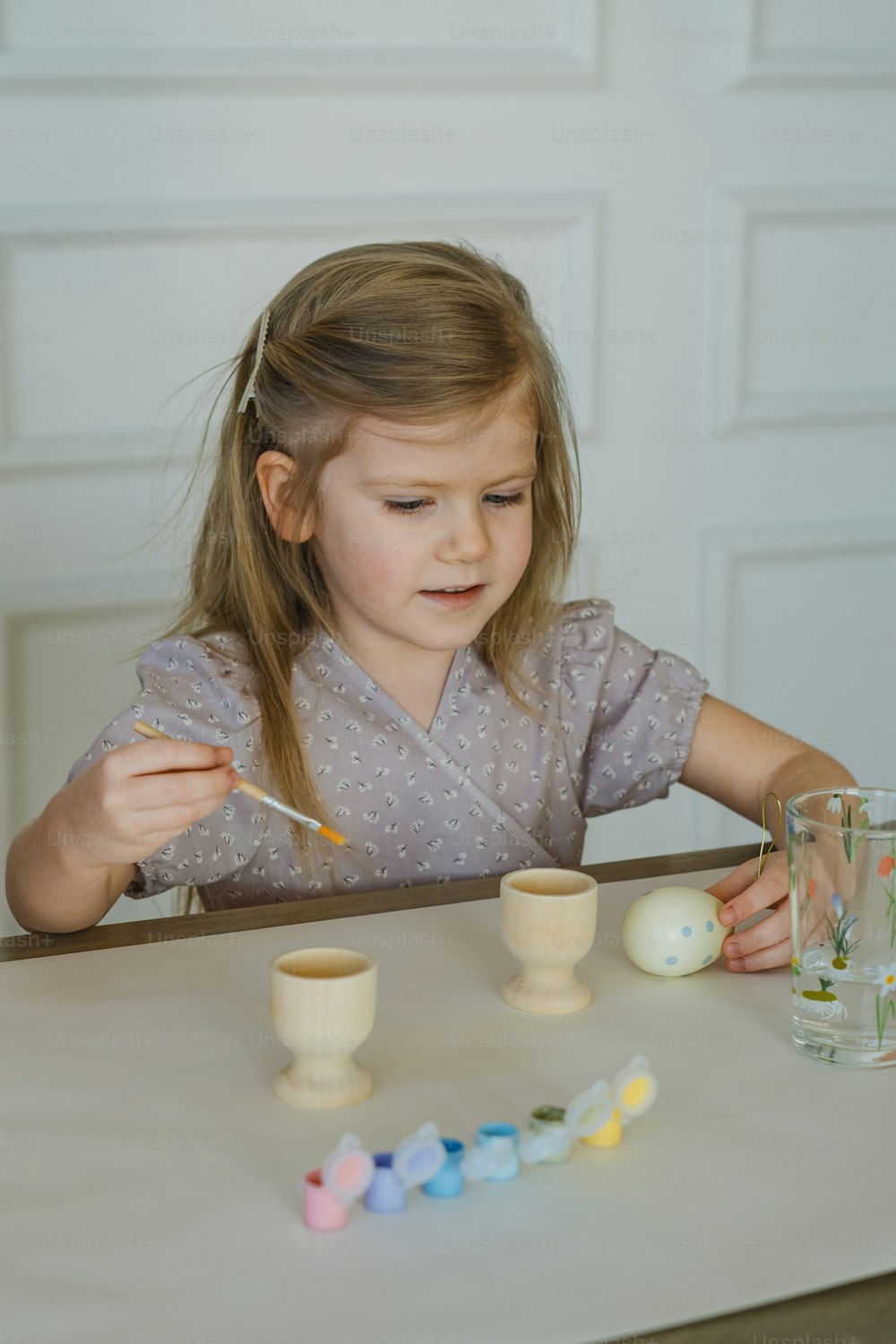 a little girl sitting at a table with a spoon in her hand