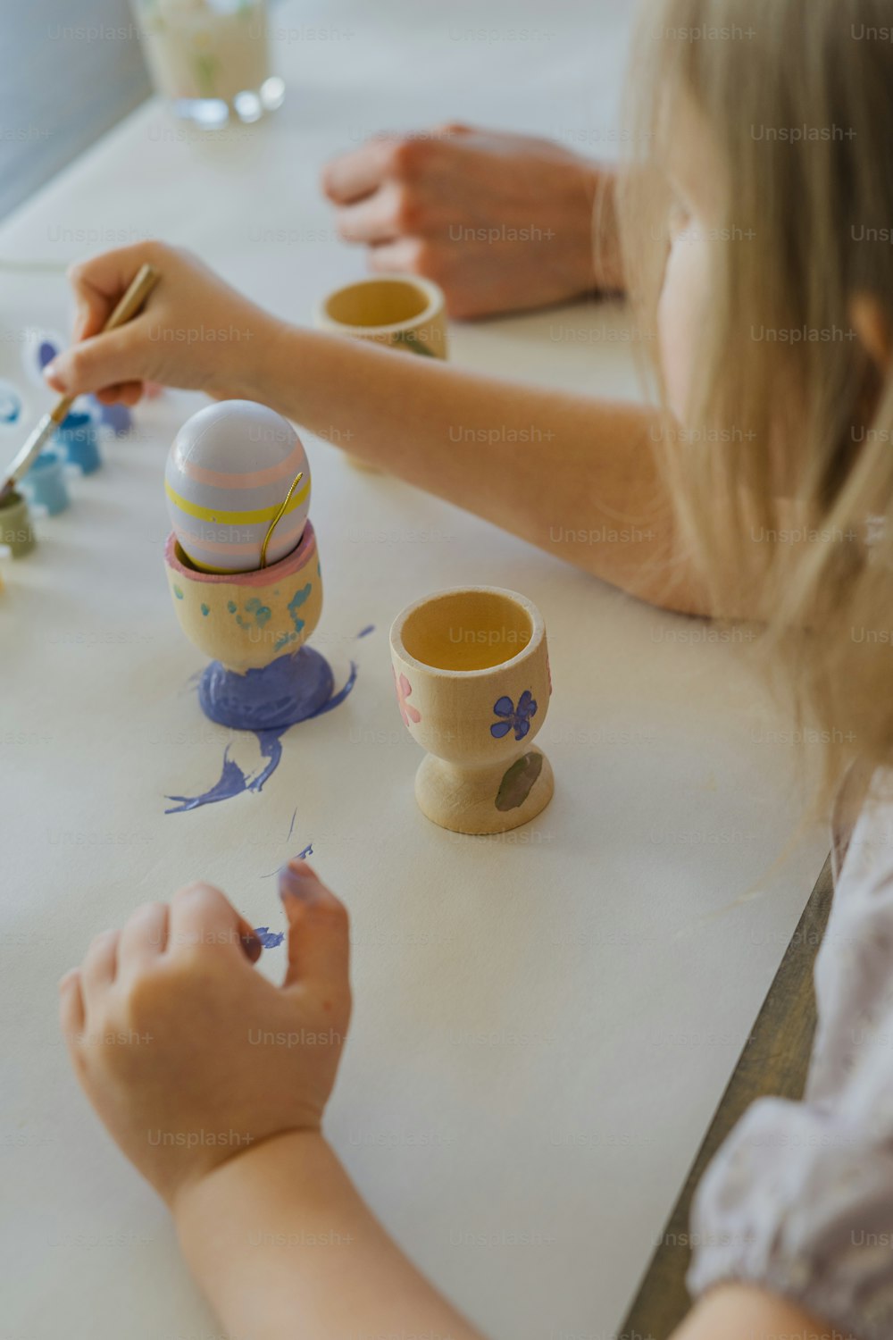 a little girl painting eggs on a table