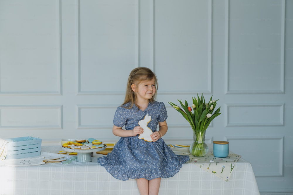 a little girl sitting on a table with a bunny