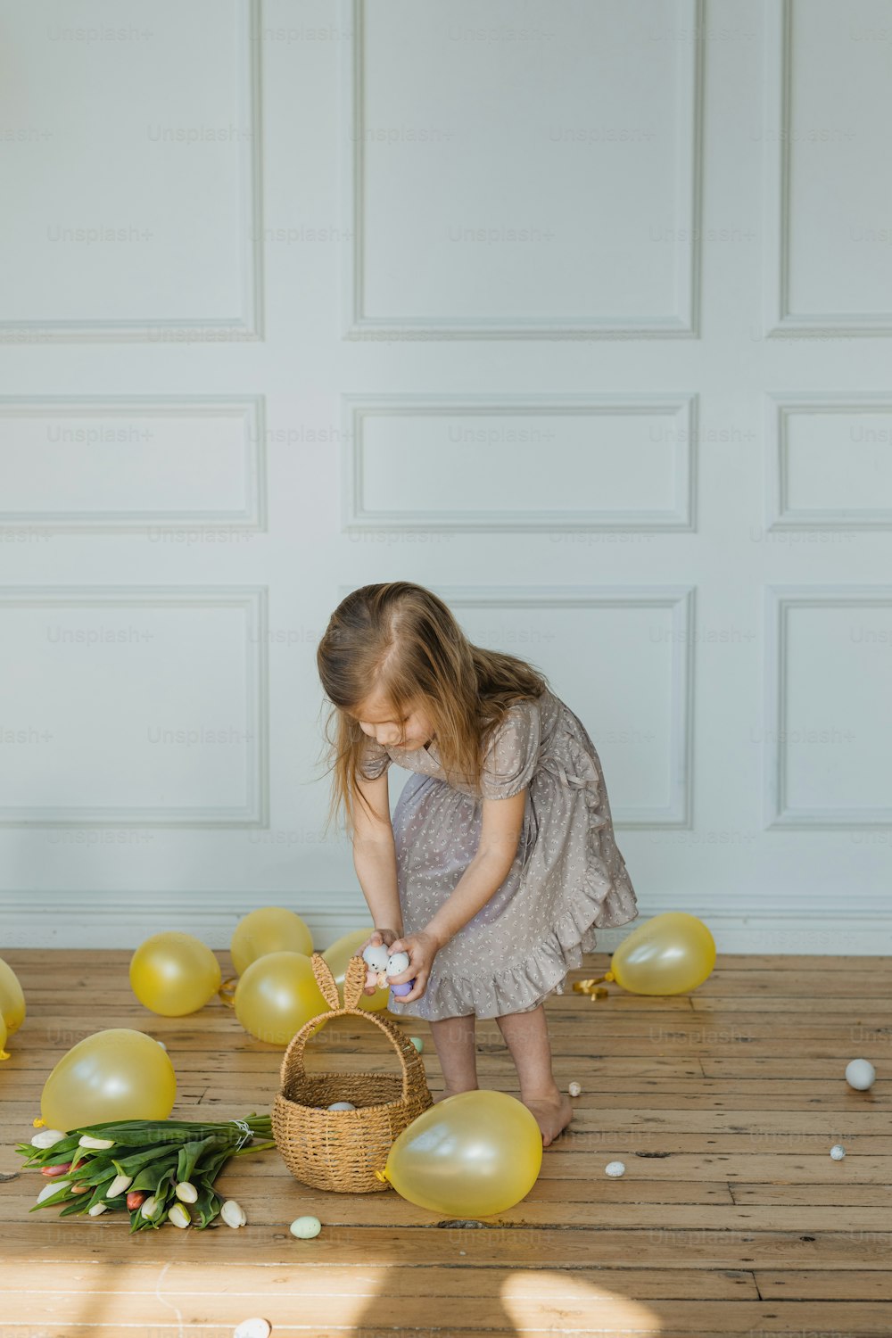 a little girl standing next to a basket filled with balloons