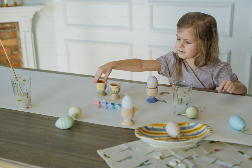 Una niña pintando huevos en una mesa