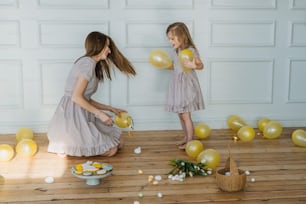 two little girls standing in front of a wall with balloons