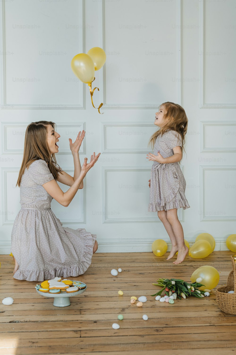 two little girls are playing with balloons and confetti