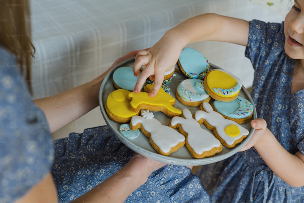 a little girl holding a plate of decorated cookies