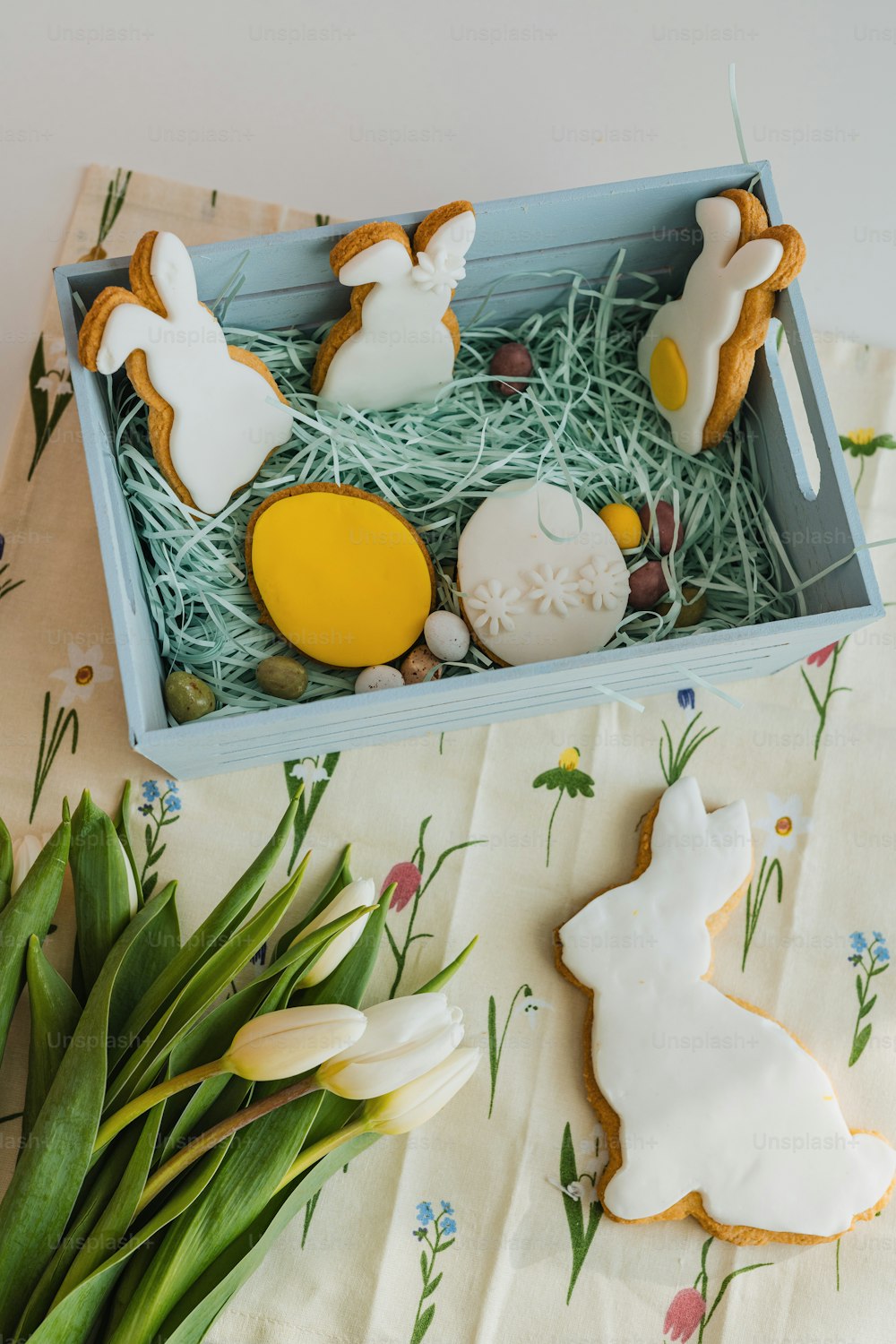 una caja de galletas decoradas y flores sobre una mesa