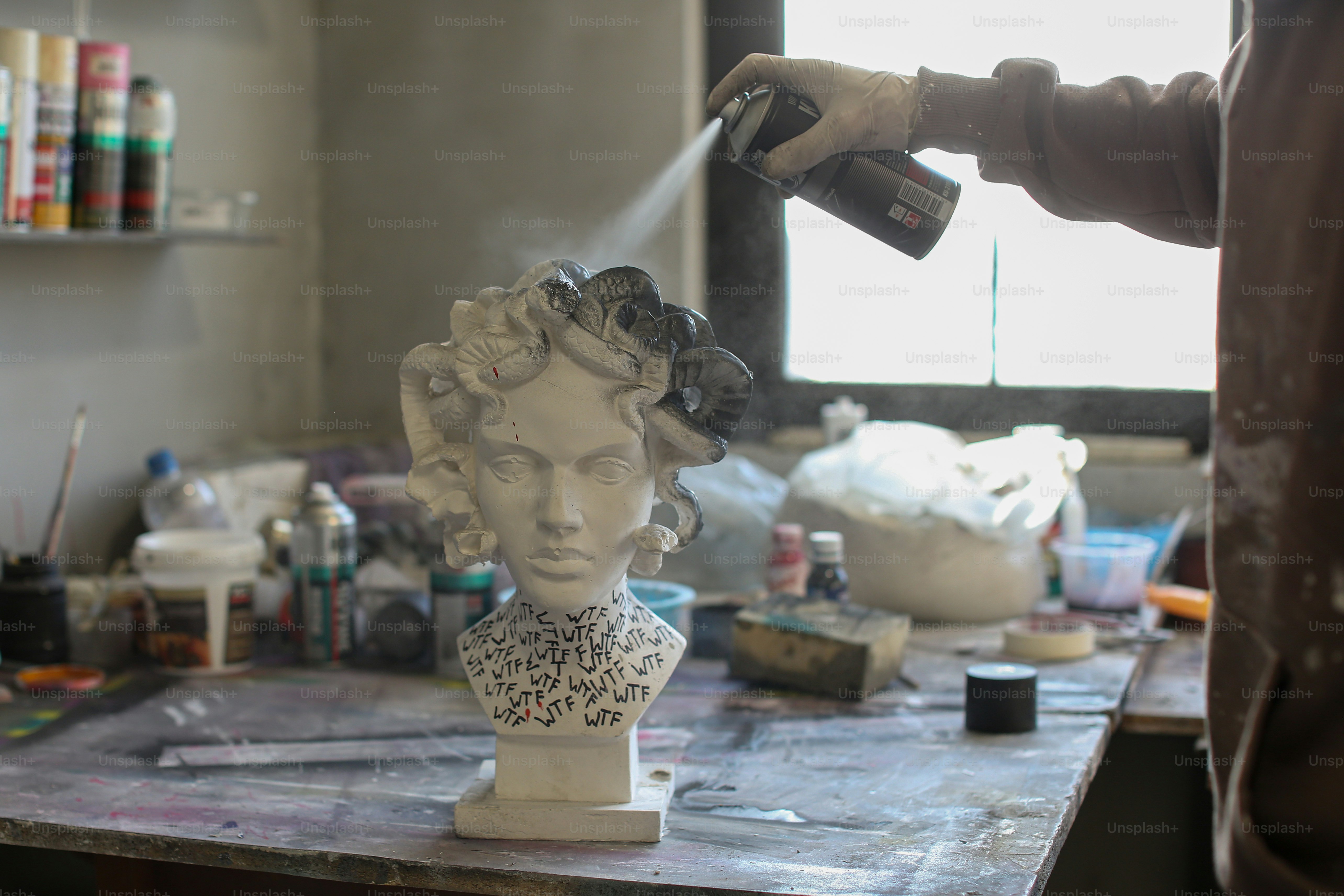 una persona che spruzza vernice su un busto di una donna