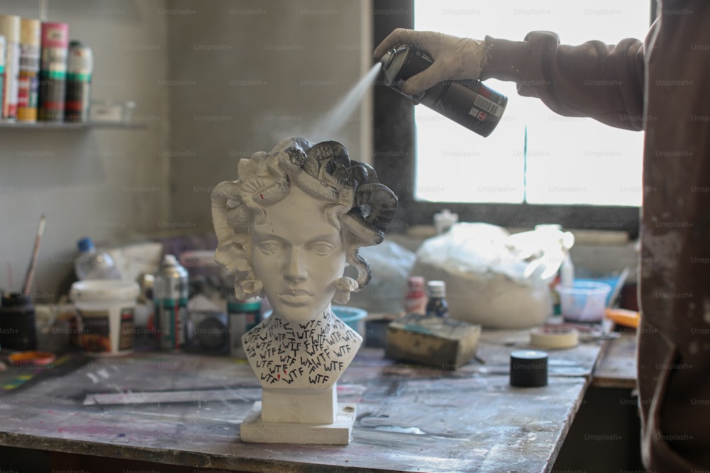 a person spraying paint on a bust of a woman