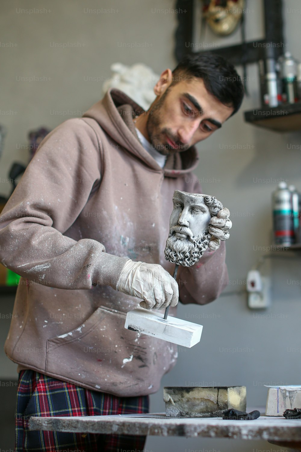 한 남자가 수염을 가진 남자의 동상을 만들고 있다