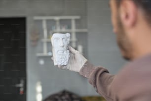 Ein Mann hält eine weiße Statue eines Mannes mit Bart