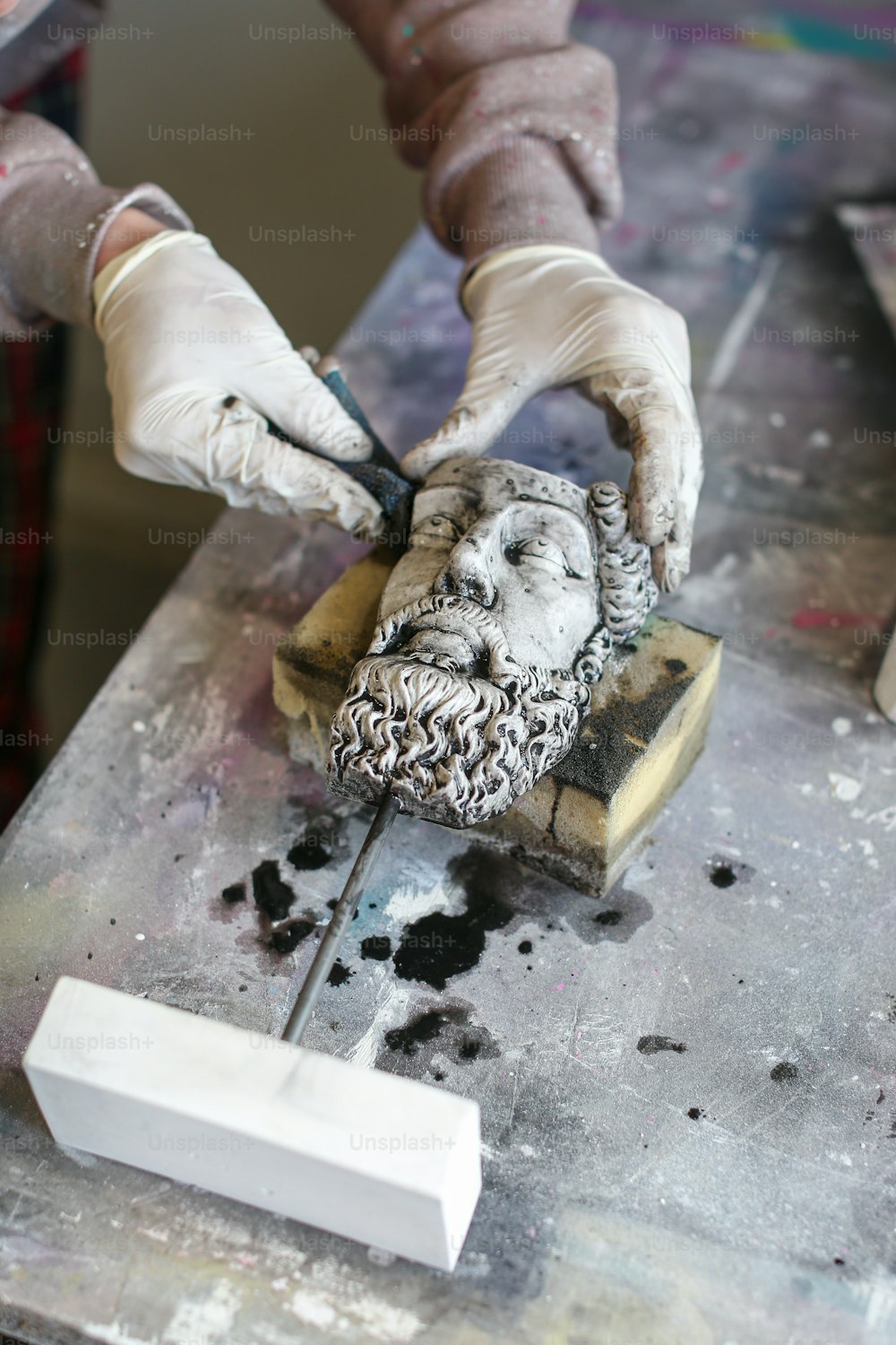 Una persona está tallando una estatua de la cabeza de un hombre