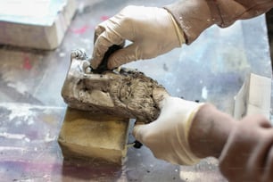 a person in white gloves and gloves working on a piece of wood