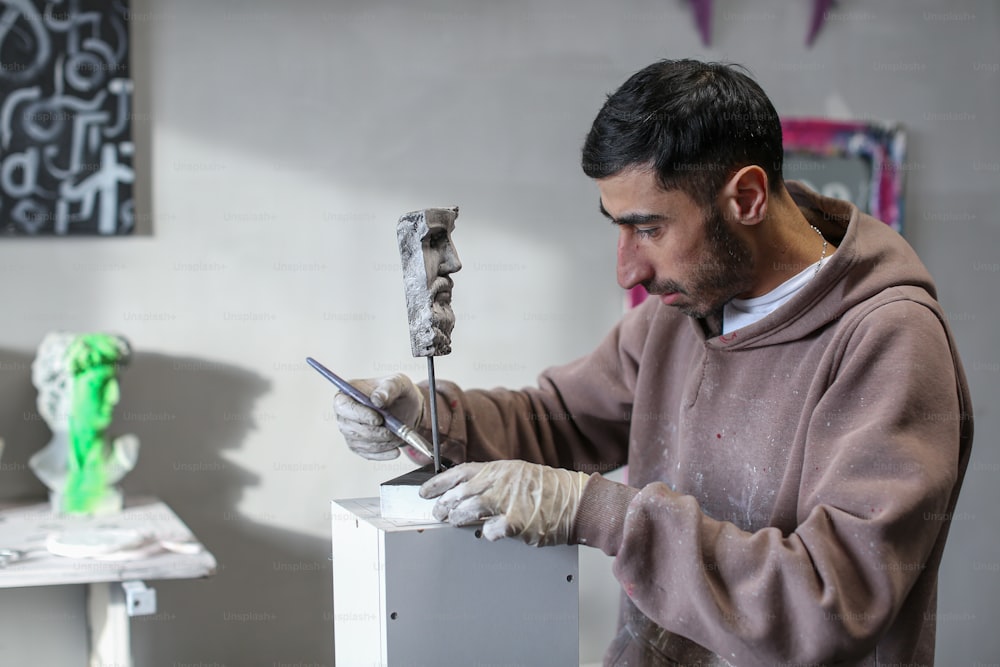 Un hombre con una sudadera con capucha marrón trabajando en una obra de arte