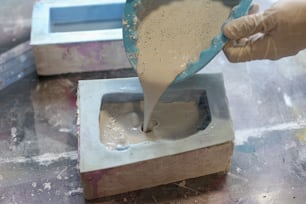 a person pouring cement into a bowl